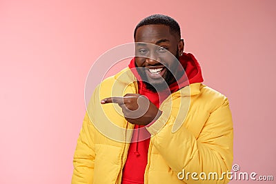 Charismatic carefree handsome black bearded guy in yellow jacket laughing friendly look camera chat pointing left show Stock Photo