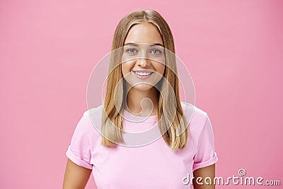 Close-up shot of friendly pleasant commong caucasian girl with fair hair and tanned skin in t-shirt smiling broadly with Stock Photo