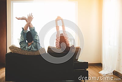 Lifestyle Couple in love and relaxing on a sofa at home and looking outside through the window of the living room. Stock Photo