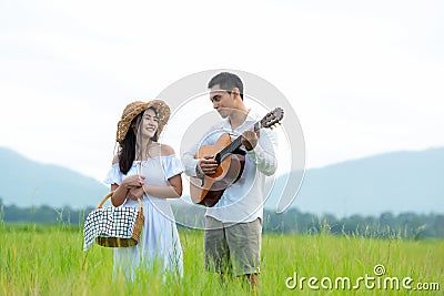Lifestyle couple picnic sunny time. Asian young couple having fun and walking relax in the meadow and field in holiday. Stock Photo