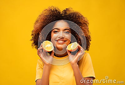 Optimist Young female model of afro appearance. Clean, even skin of the face. In the hands of citrus, orange. Stock Photo