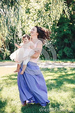 Lifestyle group portrait of smiling white Caucasian brunette mother holding hugging daughter in pink dress dancing Stock Photo