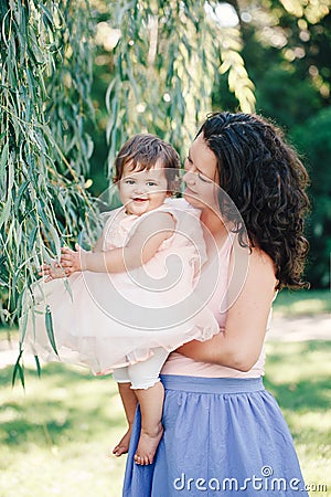 Lifestyle group portrait of smiling white Caucasian brunette mother holding hugging daughter in pink dress Stock Photo