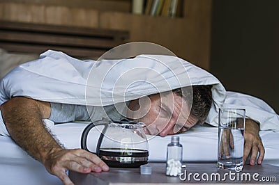 Lifestyle home portrait of young exhausted and wasted man waking up suffering headache and hangover after drinking alcohol at nigh Stock Photo