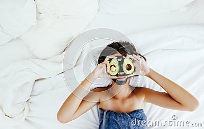 Teen girl applying black clay facial mask with avocado Stock Photo