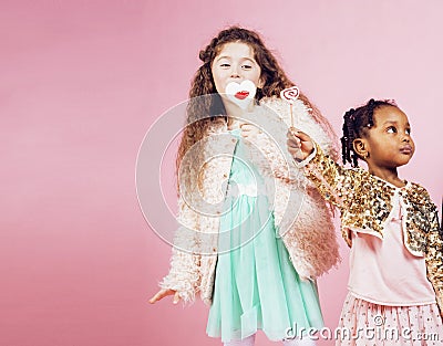 Lifestyle people concept: diverse nation children playing together, caucasian boy with african little girl holding candy Stock Photo