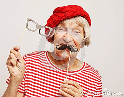 Lifestyle and people concept: funny grandmother with fake mustache and glasses, laughs and prepares for party Stock Photo