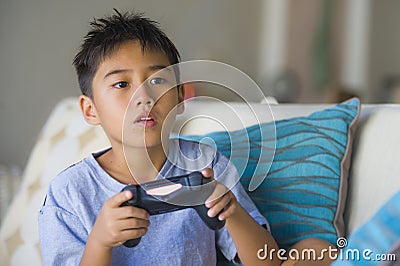 Latin young child 8 years old excited and happy playing video game online holding remote controller enjoying having fun sitting o Stock Photo