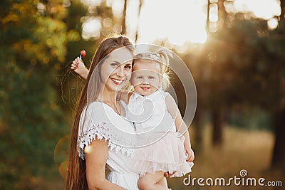 Lifestyle portrait mom and daughter in happines at the outside in the meadow. little girl with two tails Stock Photo
