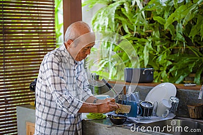 lifestyle portrait of senior happy and sweet Asian Japanese retired man cooking at home kitchen alone neat Stock Photo