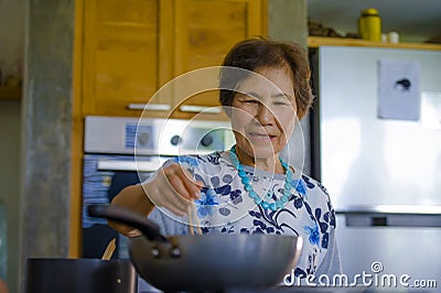 Lifestyle portrait of senior happy and sweet Asian Japanese retired woman cooking at home kitchen alone neat and tidy Stock Photo
