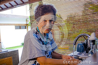 lifestyle portrait of senior happy and sweet Asian Japanese retired, woman cooking at home kitchen alone neat and tidy Stock Photo