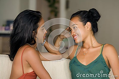 Lifestyle portrait of two young happy and relaxed Asian girlfriends having fun talking laughing and gossiping at home sofa couch s Stock Photo