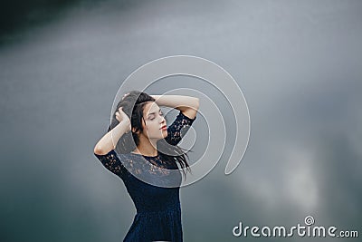 Lifestyle portrait of a woman brunette on the background of the lake in the sand on a cloudy day. Romantic, gentle, mystical Stock Photo