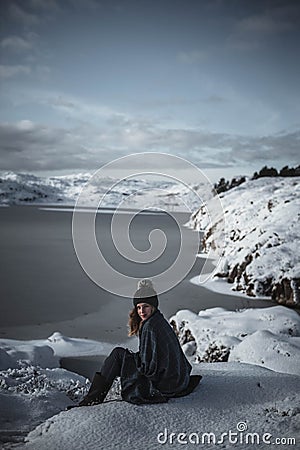 Lifestyle portrait of woman cuddled up in blanket looking into camera and enjoying amazing sunny winter day in Scandinavia. Stock Photo