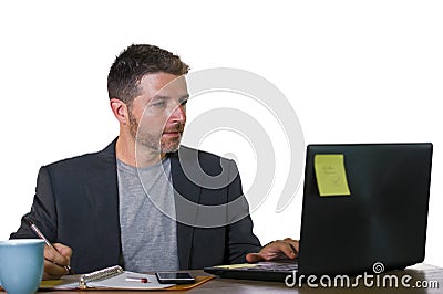 Lifestyle corporate portrait of young attractive busy and confident businessman working at office computer desk writing notes Stock Photo