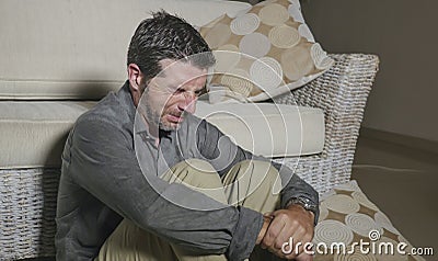 Lifestyle portrait young attractive sad and depressed man sitting on living room floor feeling desperate and stressed suffering Stock Photo