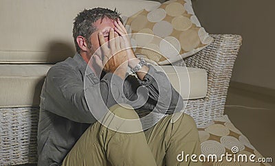 Lifestyle portrait young attractive sad and depressed man sitting on living room floor feeling desperate and stressed suffering Stock Photo