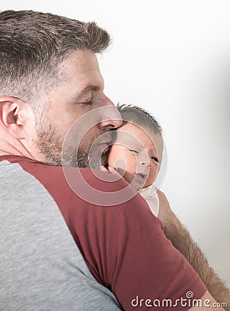 Lifestyle portrait of young father holding and kissing his daughter- an adorable and beautiful newborn baby girl portraying sweet Stock Photo