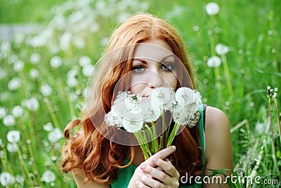 Lifestyle portrait of young spring fashion woman blowing dandelion in spring garden. Stock Photo