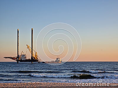 Lift boat and supply vessel setting up for an offshore wind farm at sunset in the USA. Stock Photo