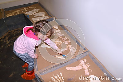 Liftle girl in pink with brush in hand digs bones Stock Photo