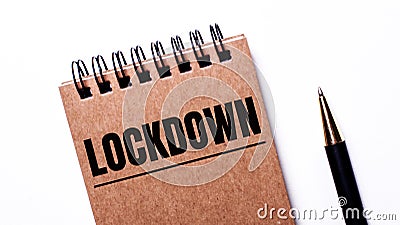 On a light background, a black pen and a brown notebook on black springs with the inscription LOCKDOWN Stock Photo