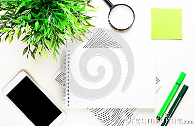 On a light background, a green plant, markers, a phone, a green sticker and a blank notepad for inserting text or illustrations. Cartoon Illustration