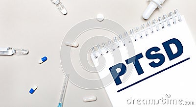 On a light background, a syringe, a stethoscope, vials of medicine, an ampoule and a white notepad with the text PTSD. Medical Stock Photo