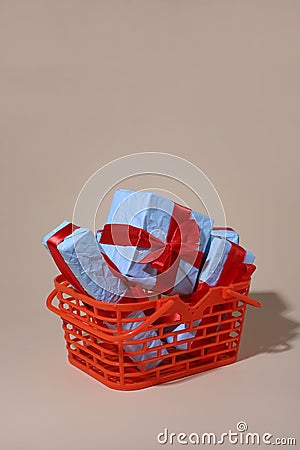 on a light background there is an orange shopping basket containing gifts in blue packaging Stock Photo