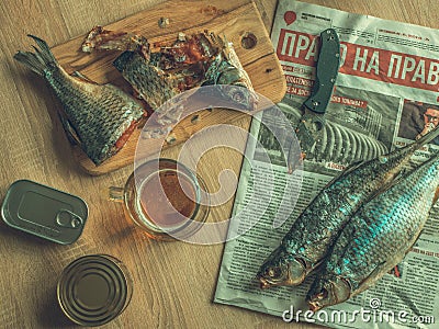 Light beer and smoked fish on the table with knife and food cans.Food concept. Editorial Stock Photo