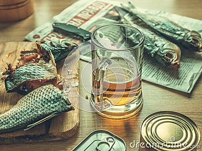 Light beer and smoked fish on the table with knife and food cans. Food concept. Editorial Stock Photo