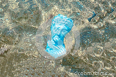 A light blue antique roman head under the sea on sandy background. Stock Photo