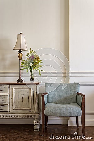 Light blue armchair and cream vintage sidebar with table lamp Stock Photo