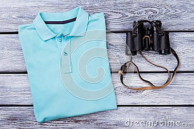 Light blue folded polo t shirt and binoculars. Stock Photo