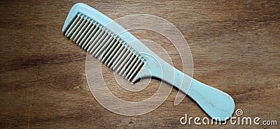 a light blue hair comb on a brown wooden background has wooden textures Stock Photo