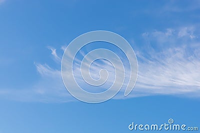 Light blue sky with expressive cirrus clouds, shaped like a feather or a wing. The shape of the cloud gives the Stock Photo