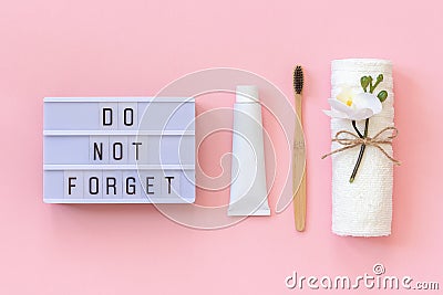 Light box text Do not forget and natural eco-friendly bamboo brush for teeth, towel, toothpaste tube. Set for washing on pink Stock Photo