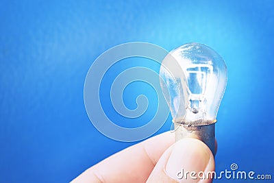 Human hand holding lamp on blue background Stock Photo