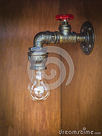 Light bulb at a water pipe with a red rotary velve Stock Photo