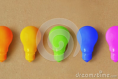 Light bulbs in different colors on recycled paper background - Concept of creativity and divergent thinking Stock Photo