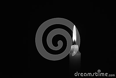 Candle burning in the black background. Black and white photo. Located on the right side of the shot Stock Photo