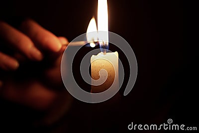 Light candle in darkness with match Stock Photo