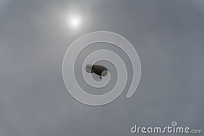 Light coloured blimp, hot air airship in grey sky. Rainy day, unearthly fantastic, but real landscape. Inflatable Stock Photo