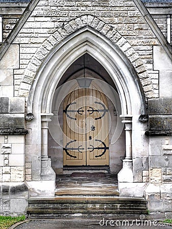Light coloured door with heavy duty hinges at the stone building entrance Stock Photo
