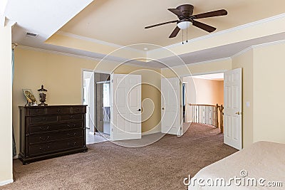 Light coloured, master bedroom with a ceiling fan, a king bed and a large dresser Editorial Stock Photo