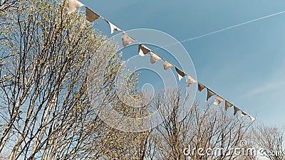 Light festive small flags of a triangular shape swaying in the wind. Clip. Bottom view of a garland of small flags on Stock Photo