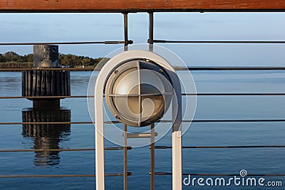 Light fixture on a ship railing, blue sky and still waters Stock Photo