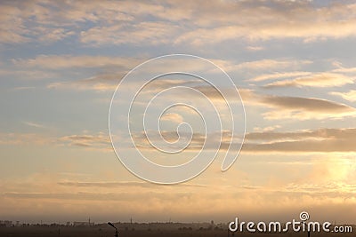 Light fog over a green field during summer sunset, gradient of colors in the sky, cloudy weather, silhouettes of trees Stock Photo