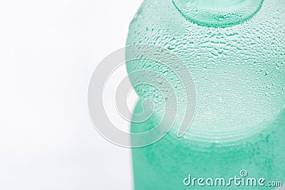 Light Green Sweated Frosty Bottle with Clear Pure Cool Water on White Background. Hydration Summer Refreshment Stock Photo
